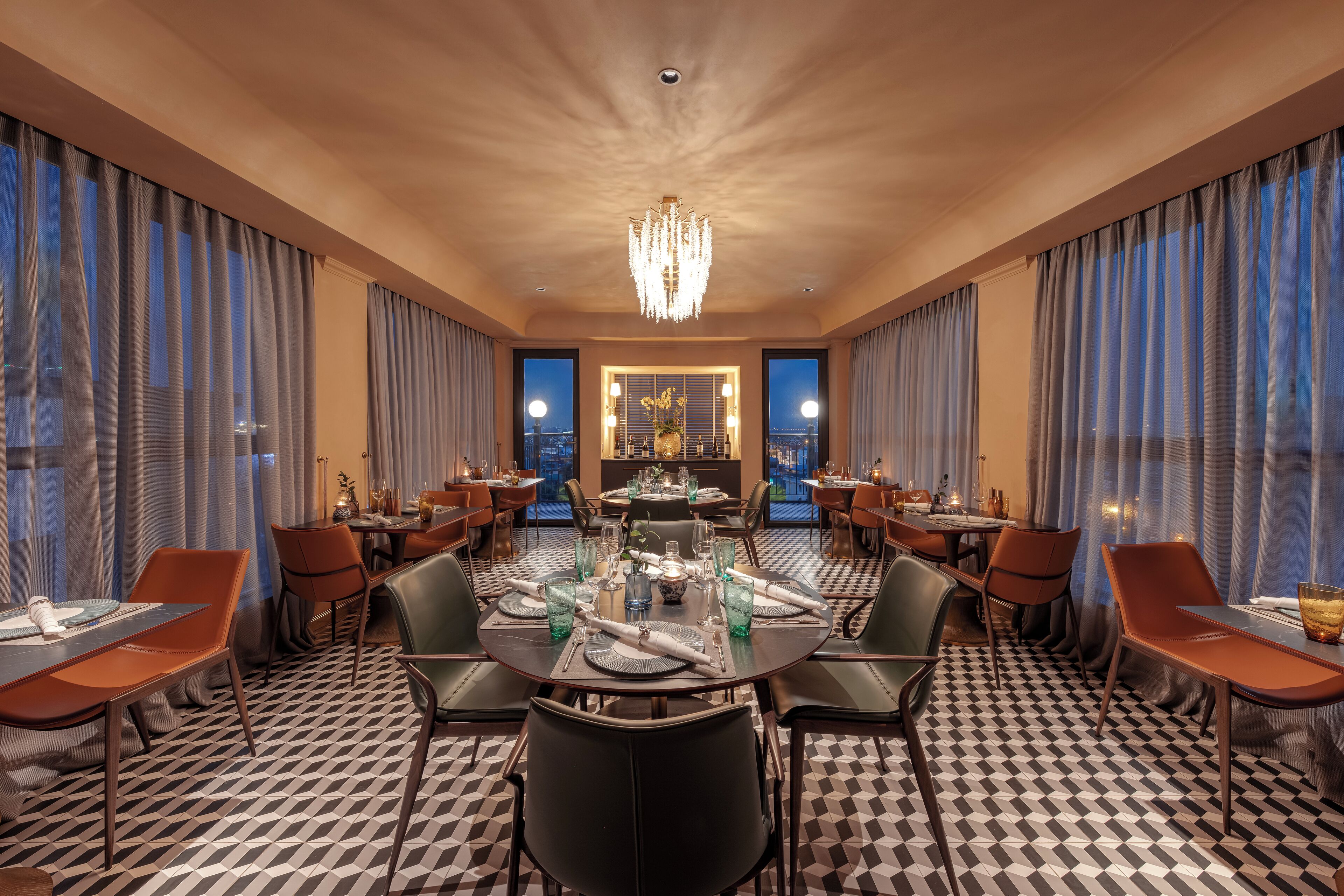 A hotel dining area with a checkered floor, round tables, and modern chairs.