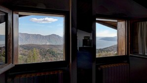 A room with a large window offering a view of mountains and a lake. - Holiday Apartment Gran Vista in Premeno with Lake Maggiore View (Premeno)