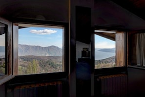 Una habitación con un amplio ventanal que ofrece vistas a montañas y a un lago.
