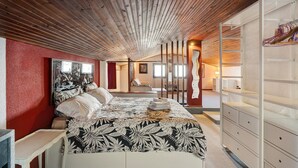 A bedroom with a wooden ceiling, a bed with a patterned bedspread, a red accent wall, and a white dresser. - Holiday Apartment Gran Vista in Premeno with Lake Maggiore View (Premeno)