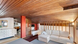 A modern interior with a wooden ceiling, a white sofa, a white dresser, and a red accent wall. - Holiday Apartment Gran Vista in Premeno with Lake Maggiore View (Premeno)