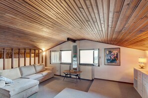 Une pièce de style « loft », avec un plafond en pente, un canapé, une table et un tableau accroché au mur.