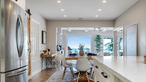 A modern kitchen with a large refrigerator, wooden dining table, and chairs. - Lakefront Luxury | Pool, Hot Tub, Wine Route (Kingsville)