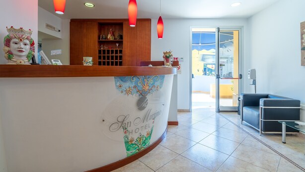 Taulell de recepció amb un logotip, un mostrador de fusta i una porta de vidre que dona a l'exterior.