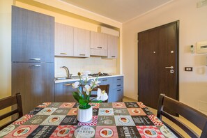 A compact kitchen with a dining table, chairs, and a vase with flowers.