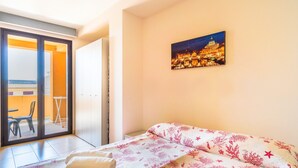Habitació d'hotel amb un llit, un quadre d'una vista urbana, una porta corredissa de vidre i vista exterior.