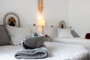 A neatly made bed with a folded gray blanket and a striped pillow.