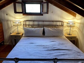 Cozy retreat with a bed, bedside tables, and a dresser, set against a rustic backdrop.