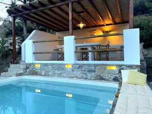 Relax by the pool surrounded by lush greenery and shaded seating.
