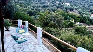 Una terraza empedrada con barandilla blanca y una silla azul.