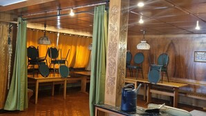 Une pièce aux murs et au plafond en bois, un coin repas avec des chaises et une table, et un meuble avec des tiroirs.