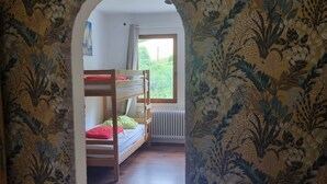 Une chambre avec un lit superposé, un radiateur et une fenêtre donnant sur un espace verdoyant.
