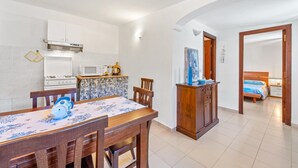Eine kompakte Küche mit Essbereich, ein Bett mit Holz Kopfteil und ein kleines Badezimmer.