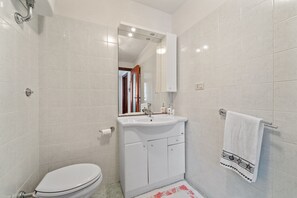 Une salle de bain équipée de toilettes, d’un lavabo, d’un miroir et d’un porte-serviettes.