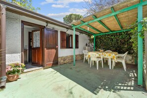 A covered patio with a table and chairs, a wooden door, and a stone wall. - Vacation Home "The Loft Of Stars" with Mountain View, Private Terrace & Wi-Fi (Torre delle stelle)