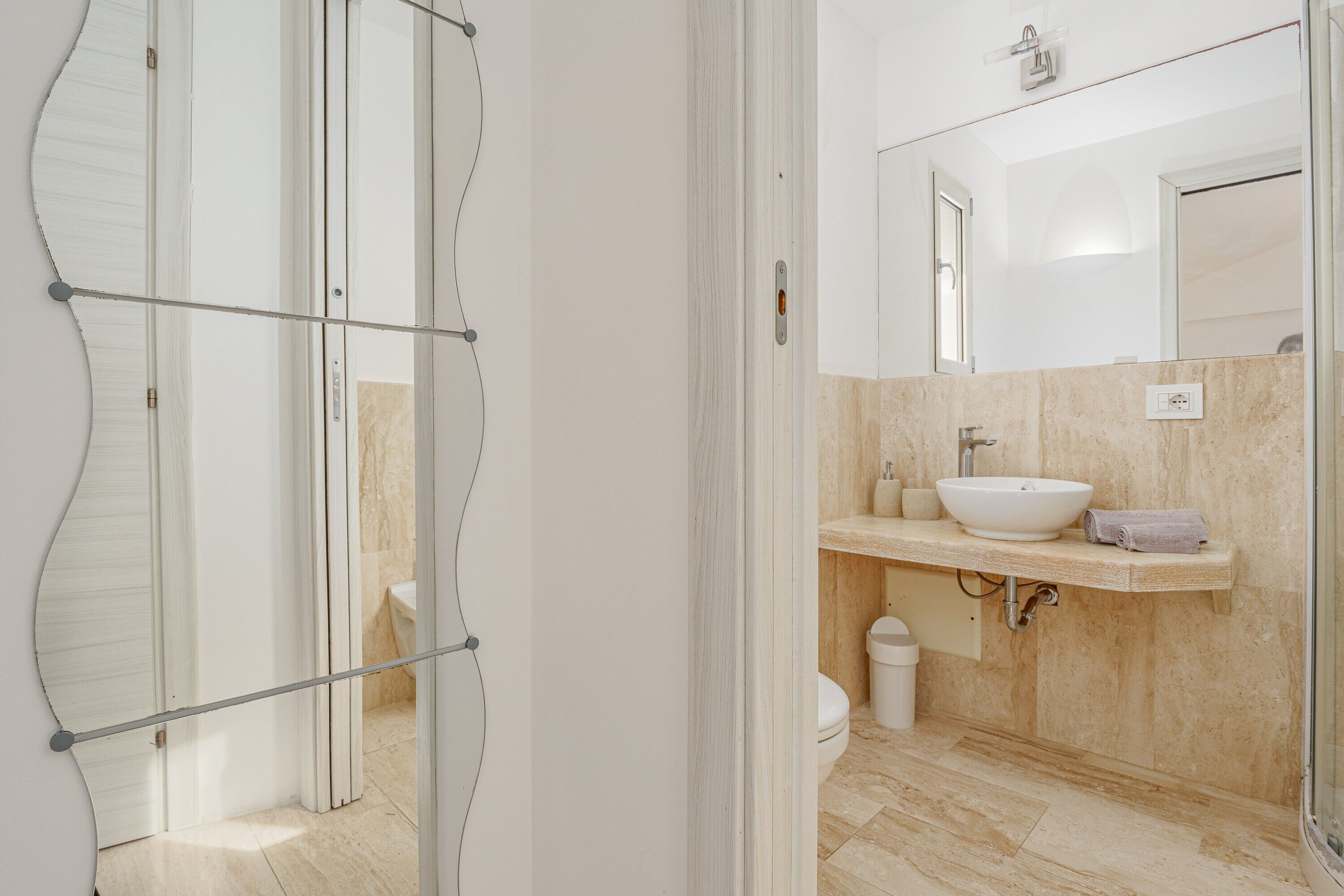 A bathroom with a white sink, a mirror, and a shower area.