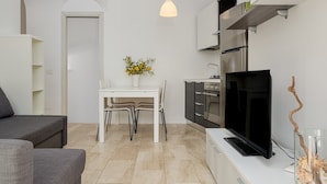 Eine moderne Küche mit Fernseher, Esstisch und Stühlen.