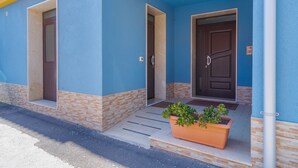 Un edificio con paredes azules, dos puertas y una planta en maceta en el porche.