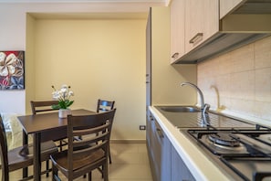 A compact kitchen with a gas stove, sink, and wooden dining table with chairs.
