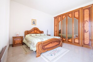 A bedroom with a wooden bed, a nightstand, a dresser, and a mirror.