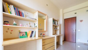 Una stanza con una scrivania in legno, scaffali con libri, uno specchio e una porta.
