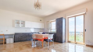 Una cucina moderna con mobili bianchi, un tavolo da pranzo con sedie e un'ampia finestra con vista.