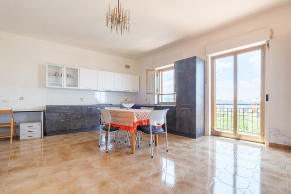 A modern kitchen with white cabinets, a dining table with chairs, and a large window with a view.