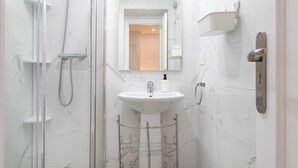 Une salle de bain avec une douche à parois de verre, un lavabo sur pied blanc et un miroir au-dessus du lavabo.
