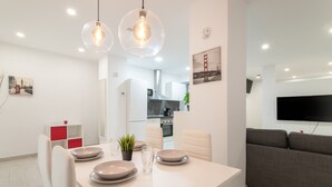 Un espace de vie moderne comprenant un coin repas, une cuisine et un grand téléviseur à écran plat.
