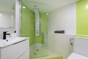 Ein Badezimmer mit Dusche, Waschbecken und Spiegel.