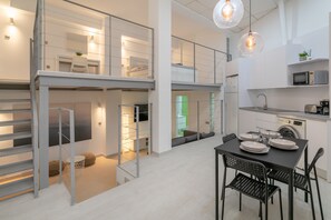 Un intérieur moderne comprenant un coin repas, une cuisine et un escalier menant à un niveau supérieur.
