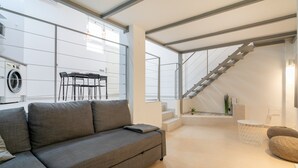 A modern living room with a sofa, a dining table, and a staircase. - Holiday Apartment "Alison's Loft" with A/C & Wi-Fi (Alicante)
