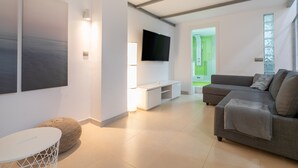 A modern living room with a flat-screen TV, a grey sofa, a white coffee table, and a large abstract painting on the wall. - Holiday Apartment "Alison's Loft" with A/C & Wi-Fi (Alicante)