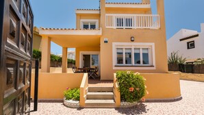 A two-story building with a balcony, a door, and a small patio area with a table and chairs.