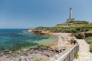 A coastal landscape with a lighthouse, clear blue sea, rocky shore, and a stone pathway. - Holiday Home 'La Cala' with Sea View, Wi-Fi and Air Conditioning (Cabo de palos)