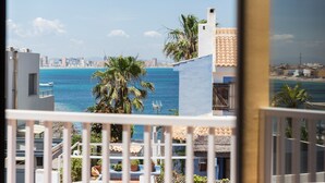 A balcony with a view of the sea and cityscape, including buildings and palm trees.