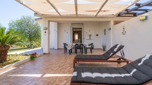 A covered outdoor area with lounge chairs, a table with chairs, and a view of the garden. - Vacation Home "San Lorenzo" with Private Terrace, Private Garden and A/C (San Lorenzo)