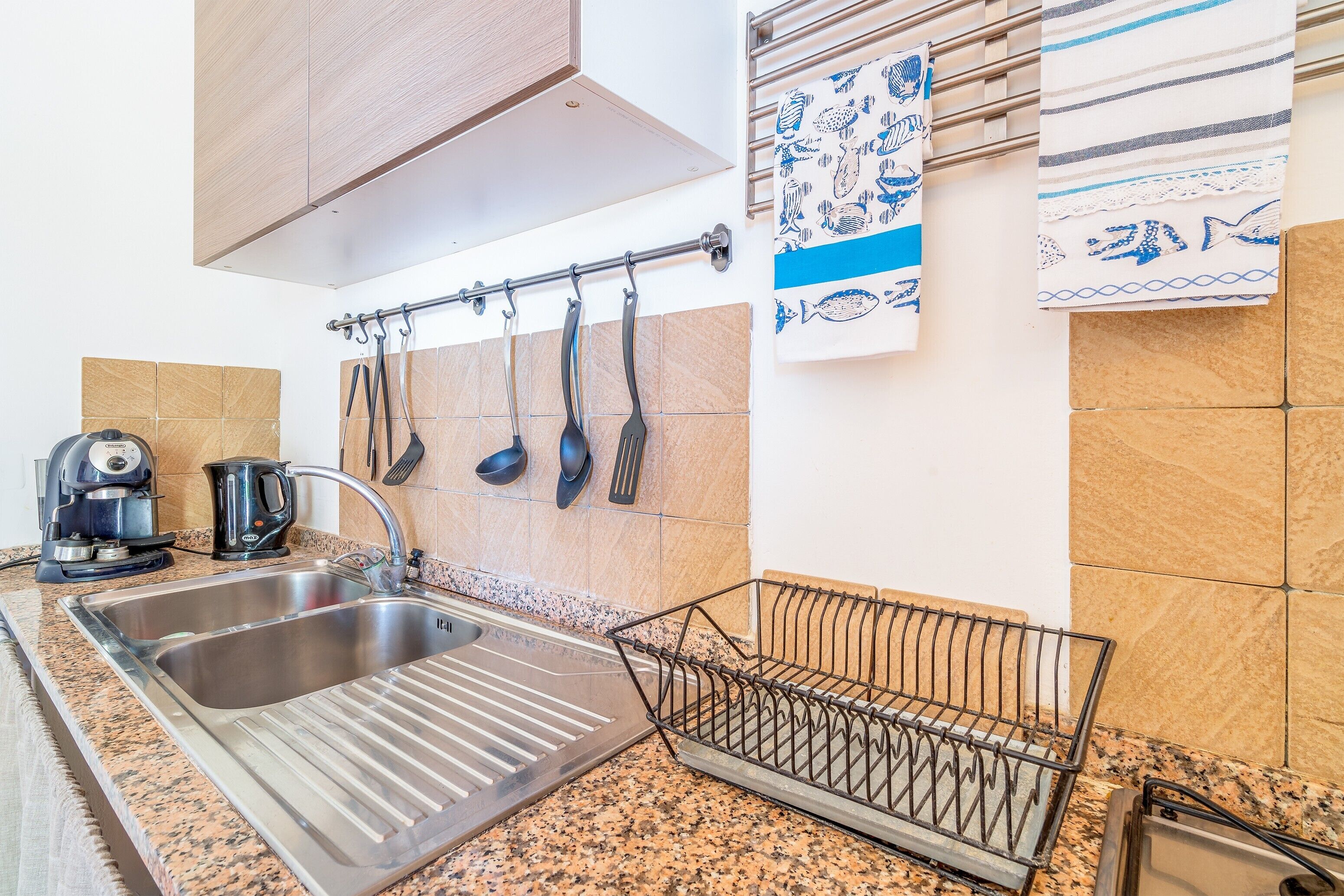 A kitchen with two sinks, a coffee maker, and a dish rack.