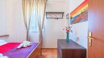 Ein Hotelzimmer mit Bett, Schminktisch, einem Gemälde und einem Fenster mit Vorhängen.