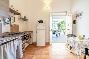 A compact kitchen with a refrigerator, stove, and dining area with a table and chairs.