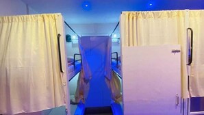 A narrow corridor with bunk beds on either side, leading to a central area with a blue-lit ceiling. - Golden Star Dormitory (Mumbai)