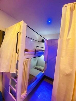 Habitación con literas, ventilador de techo, ventana pequeña y puerta.