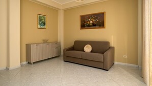 A living room with a sofa, a cabinet, and two framed floral paintings on the walls.