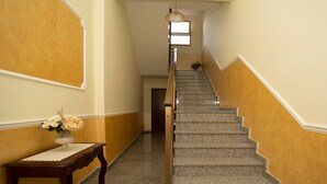 A staircase with a handrail, a vase with flowers, and a hanging light fixture.