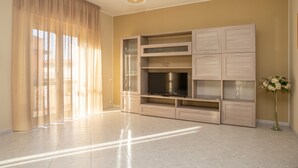 A spacious living area with a large flat-screen TV, built-in shelves, and a vase of flowers.