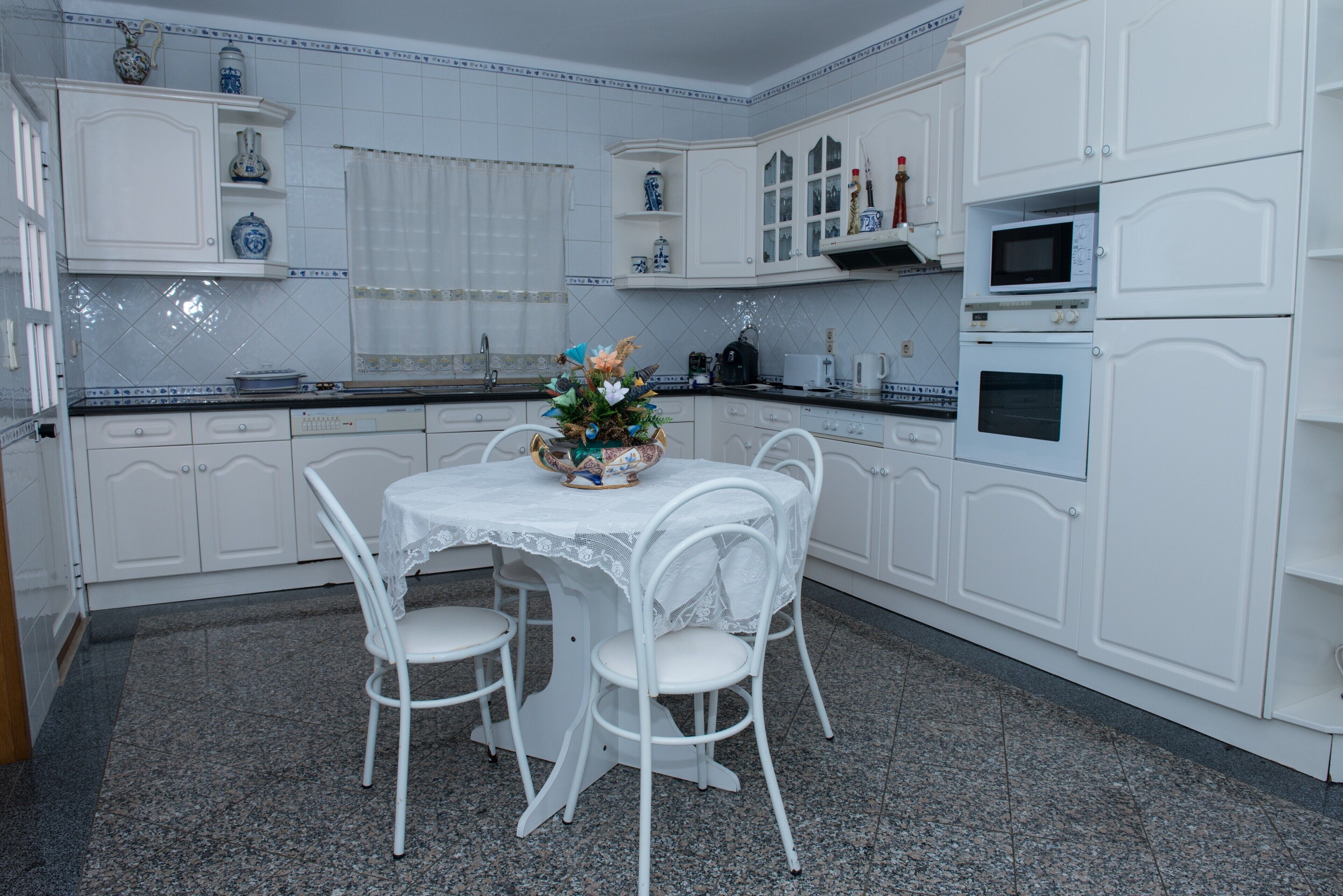 Une cuisine avec des meubles blancs, une table à manger avec des chaises et un élément décoratif au centre.