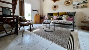 A cozy living room with a sofa, a coffee table, and a wicker chair. There is a wooden ceiling and a window with curtains. - House for 4 with Wifi near the beach in Dolus-d'Oléron (Dolus-d'Oléron)