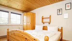 Una cama de madera en una habitación con techo inclinado y ventana.