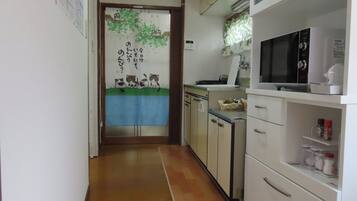 Een koelkast, een magnetron, een kookplaat, kookgerei, borden en bestek