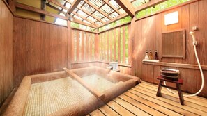 Ein Holz-Spa mit Whirlpool, einer hölzernen Bank und einem kleinen Tisch mit Flaschen.